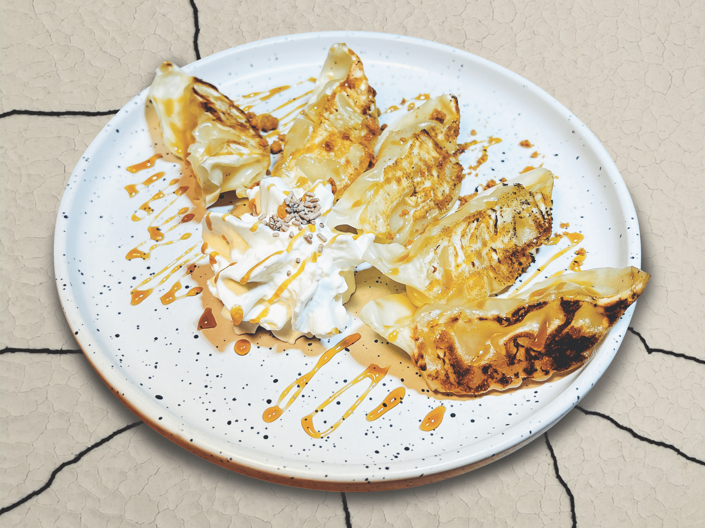Des gyoza farcis aux pommes, légèrement caramélisés, servis avec une garniture de chantilly et sauce caramel